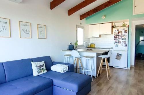 un salon avec un canapé bleu et une cuisine dans l'établissement La Parenthèse Marine, à Bandol
