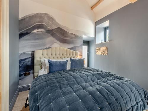 a bedroom with a large bed with a painting on the wall at Cattle Cake Cottage in Askham