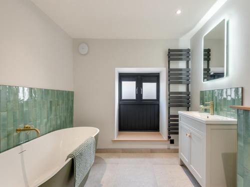 a bathroom with a tub and a sink and a door at Cattle Cake Cottage in Askham