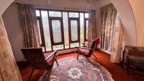 a room with two chairs and a large window at Abshar Heritage Villa in Srinagar