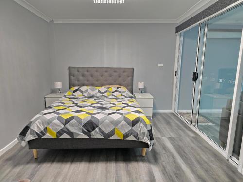 a bedroom with a bed with a yellow and grey comforter at Shepparton Central Guest Suite in Shepparton