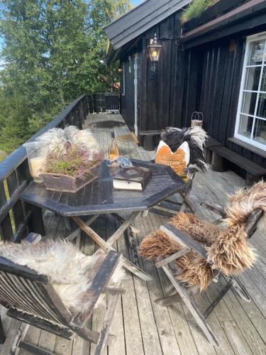 einen Picknicktisch und Stühle auf einer Holzterrasse in der Unterkunft Bekkeli; Mountain cabin, amazing view - ski in - ski out, golf, hike, bike,, fishing, in Nes i Ådal