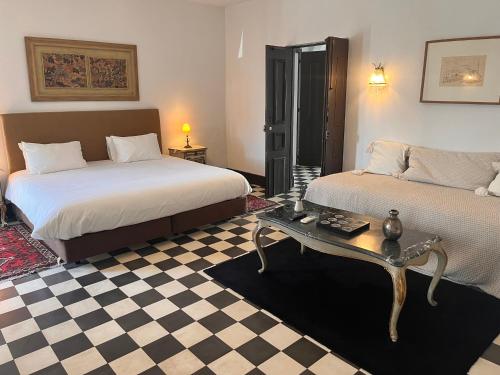 a hotel room with two beds and a table at Palacete da Real Companhia do Cacau - Royal Cocoa Palace in Montemor-o-Novo