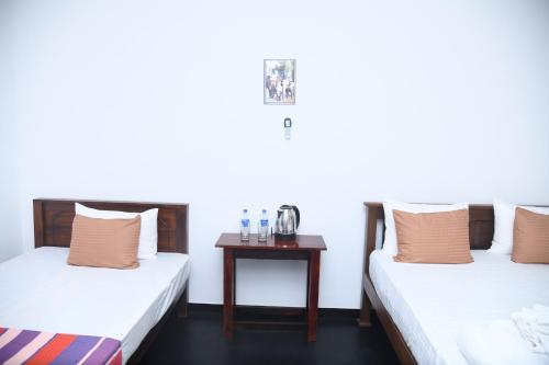 two beds in a room with a table at TESHI SAFARI VILLA in Udawalawe
