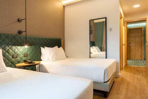 a hotel room with two beds and a mirror at Hilton Garden Inn Milan Malpensa in Somma Lombardo