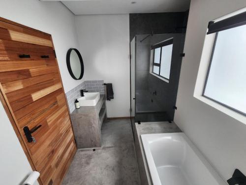 a bathroom with a tub and a sink and a mirror at Bald Ibis (856 Highland Gate) in Dullstroom