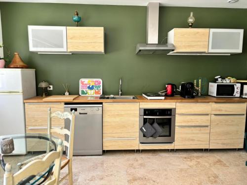 uma cozinha com armários de madeira e um forno com placa de fogão em Maison dans la pinède em Rognes