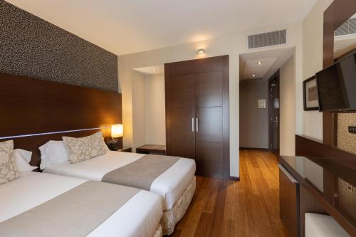 a hotel room with two beds and a television at Barcelona Hotel Colonial in Barcelona