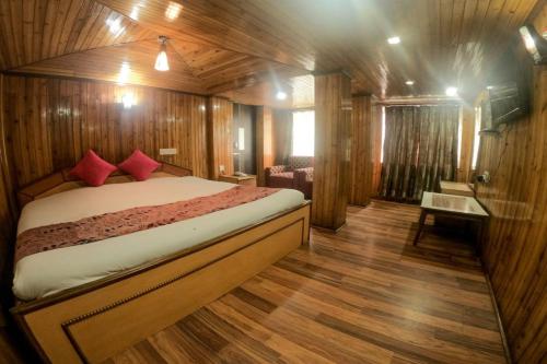 Hotel Broadway Mall Road Darjeeling - Family Joy Vacations & Best Location في دارجيلنغ: غرفة نوم بسرير في غرفة خشبية