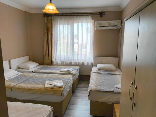 エディルネにあるTac Pansiyonのベッド3台と窓が備わる客室です。