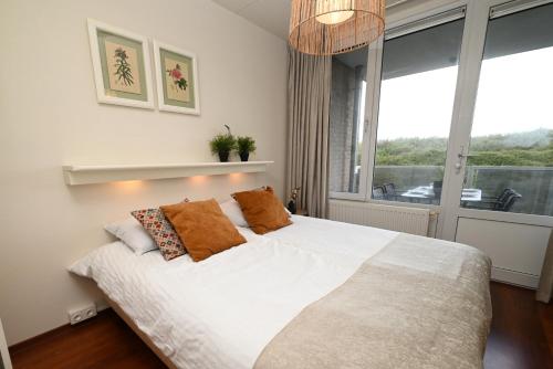 een slaapkamer met een wit bed met kussens en een raam bij Fika - Résidence Deurloo 55-10 in Cadzand