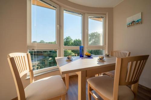 a dining room with a table and chairs and windows at Moana Sunset Apartment in Ahtopol