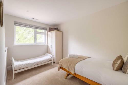 a white bedroom with a bed and a window at Windsor Charm Spacious 3-Bed, Parking & Garden - By Tempstay in Windsor