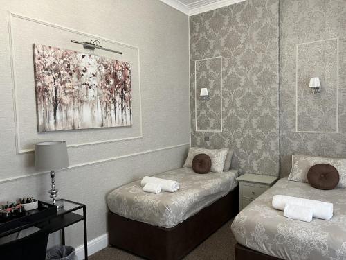 a room with two beds and a painting on the wall at Tanes Hotel in Cardiff