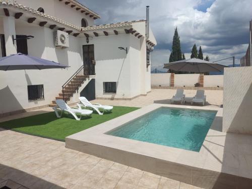 a villa with a swimming pool with chairs and umbrellas at El rincón de la buena vista in Las Gabias