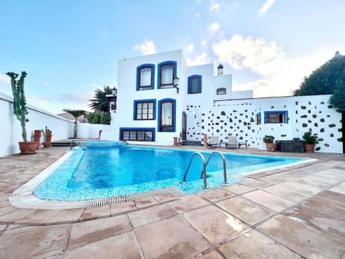 a villa with a swimming pool in front of a house at Room with breakfast included, balcony, WiFi, pool in Yaiza in Yaiza