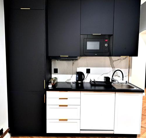 cocina con armarios negros y microondas en Kopernik Premium Rooms Apartment, en Toruń