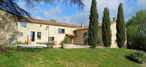 una grande casa in pietra con alberi nel cortile di Clos Baroanni - Studio La Volière a Terraube