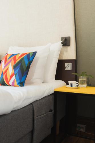 a bed with white sheets and a colorful pillow and a table at Hotel Klaus K in Helsinki