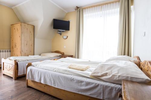 two beds in a bedroom with a tv on the wall at Willa Sport in Zakopane