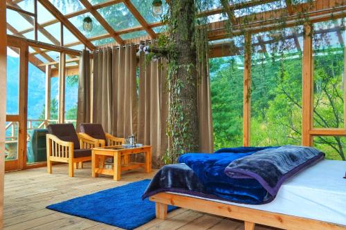 a bedroom with a bed in a glass house at Stargazing Treehouse Himachal in Sainj