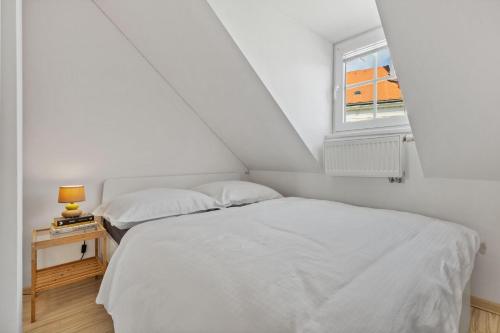 two beds in a white room with a window at Apple apartment in Bratislava
