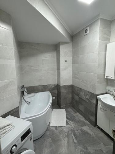 a bathroom with a white tub and a sink at Dendrarium Park Apartament in Chişinău