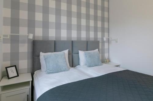 a bedroom with a bed with blue and white pillows at Na Skraju Lasu e-apart in Jastrzębia Góra