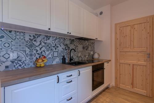 a kitchen with white cabinets and a counter top at Na Skraju Lasu e-apart in Jastrzębia Góra