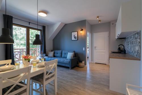 a living room with a table and a blue couch at Na Skraju Lasu e-apart in Jastrzębia Góra