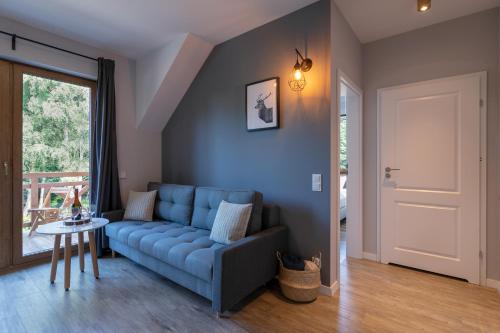 a living room with a blue couch and a table at Na Skraju Lasu e-apart in Jastrzębia Góra