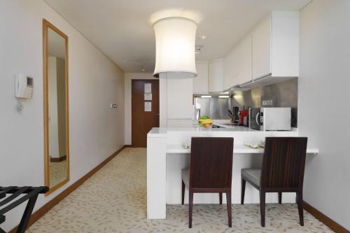 a kitchen with a white counter and two chairs at Maison Privee - Fabulous Studio with Direct Burj Khalifa Views in Dubai