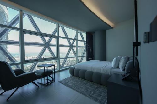 a bedroom with a bed and a chair and a large window at J 22 Residence in Lusail
