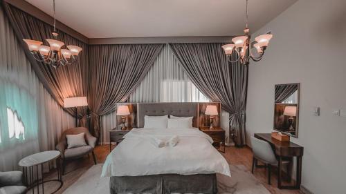 a bedroom with a large bed and a desk and chairs at HOOUD Apartments in Khor Fakkan