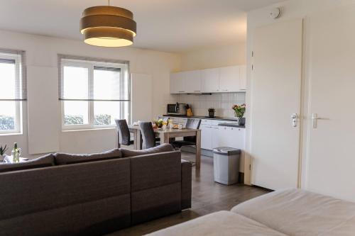 a living room and kitchen with a couch and a table at Strand Appartementen Wemeldinge in Wemeldinge