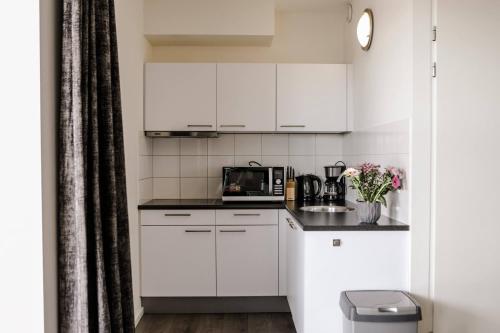 a kitchen with white cabinets and a microwave at Strand Appartementen Wemeldinge in Wemeldinge