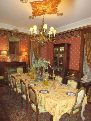 une salle à manger avec une table, des chaises et un lustre dans l'établissement Johnstone Mansion, à Keokuk