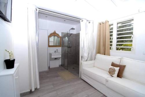 a white living room with a white couch and a mirror at La Source Guest House in Orient Bay