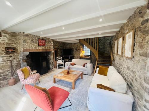 un salon avec des canapés et un mur en pierre dans l'établissement La campagne et la mer, à Tourville-sur-Sienne