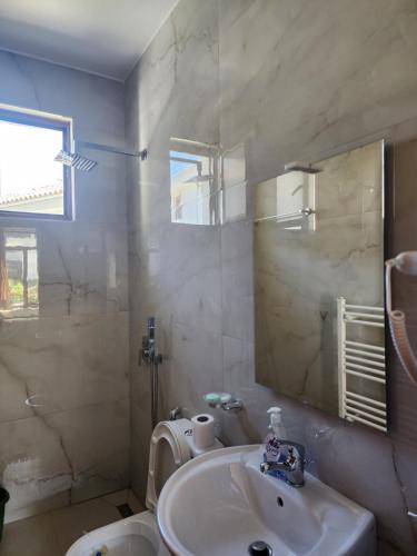 a bathroom with a sink and a toilet and a mirror at Dhami Apartment in Gjirokastër