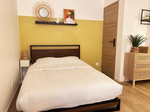 sypialnia z łóżkiem i żółtą ścianą w obiekcie Selva - Studio cosy et chaleureux w mieście Saran
