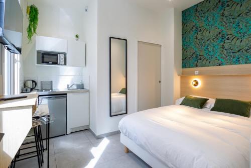 une chambre avec un grand lit blanc et une cuisine dans l'établissement Appartement 1 proche de la gare et du centre ville, à Amiens