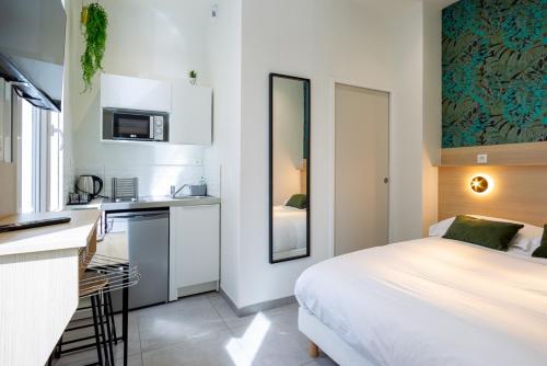 une chambre blanche avec un lit et une cuisine dans l'établissement Appartement 1 proche de la gare et du centre ville, à Amiens