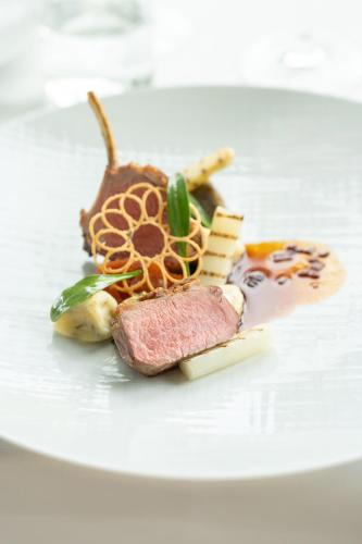 a white plate with a piece of meat and cheese at Hotel Winselerhof by Flow in Landgraaf