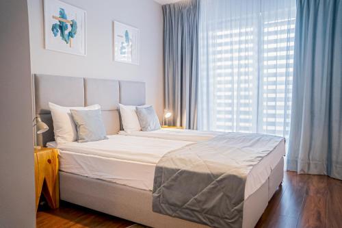 ein Schlafzimmer mit einem großen Bett und einem großen Fenster in der Unterkunft Blue Mare Solna 205 in Kołobrzeg