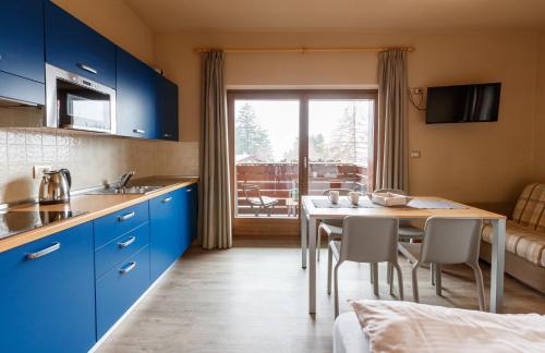 ボルミオにあるLa Villa Feleitのキッチン(青いキャビネット、テーブル、椅子付)