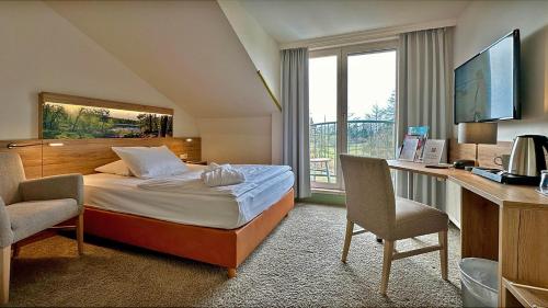 KremmenにあるHotel & SPA Sommerfeld - Adults Onlyのベッド、デスク、窓が備わるホテルルームです。