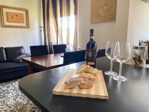 einen Tisch mit einer Flasche Wein und ein Schneidebrett mit Weingläsern in der Unterkunft Casa d'artista in Val di Chiana in Sinalunga