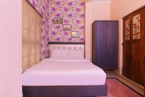 a bedroom with a white bed with a purple wall at FabHotel Poorv Sight in Varanasi