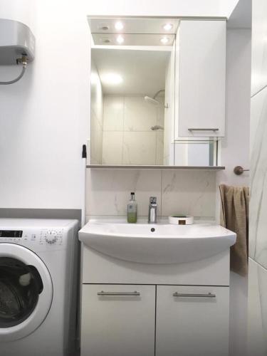 een witte badkamer met een wastafel en een wasmachine bij Apartments Ines - cozy studio in Zagreb